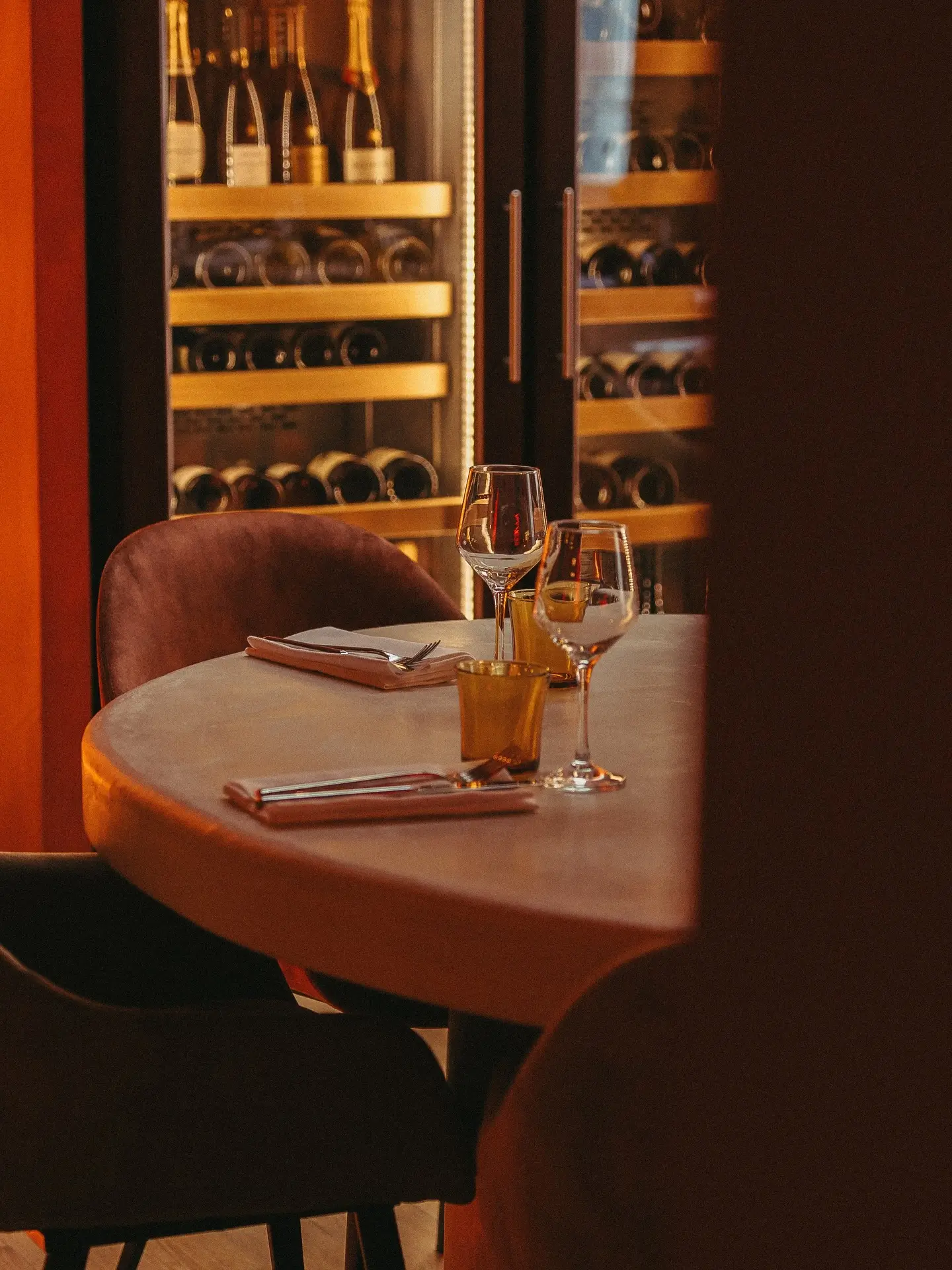 Une table ronde dressée pour deux devant les caves à vin vitrées